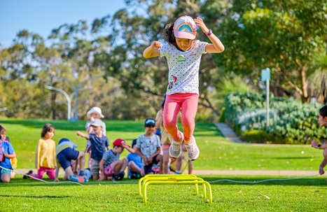 Young girl jumping outdoors at Kids Sports Club holiday program