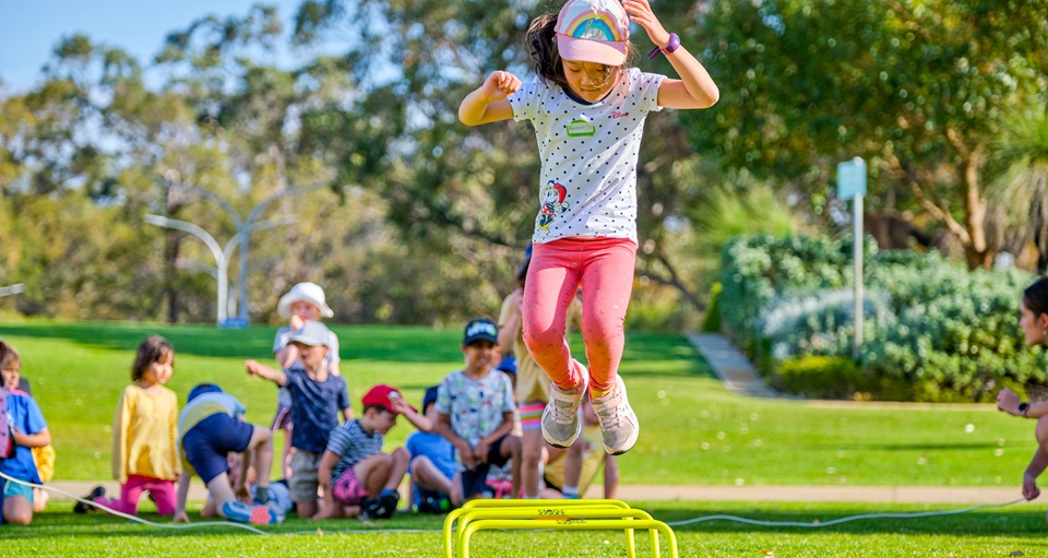 Young girl jumping outdoors at Kids Sports Club holiday program